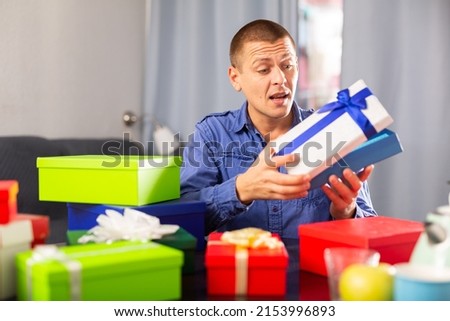 Cheerful adult man opening box with gift, celebrating his birthday