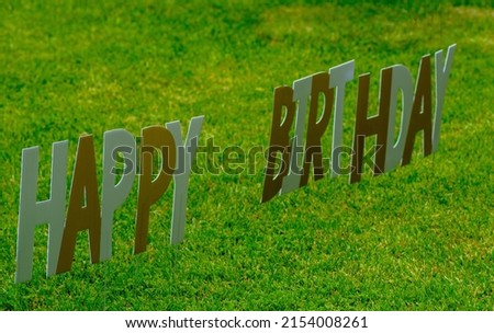 Happy Birthday yard sign for a drive by celebration. Different color letters floating against a green lawn background. Celebrate born day in the park with letters spelling happy birthday.