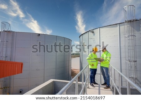 Two Asian male industrial engineers use a laptop or notebook to work on a plan, inspect work in an engineering factory. utilities Sewers and central wastewater treatment plants Royalty-Free Stock Photo #2154018697