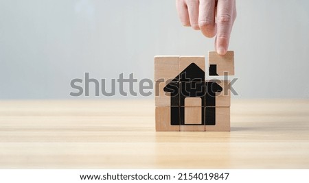 Real Estate Market Growth Concept. businessman or a home or real estate broker. taxes and profits. Wooden cube block puzzle with pictures at home
