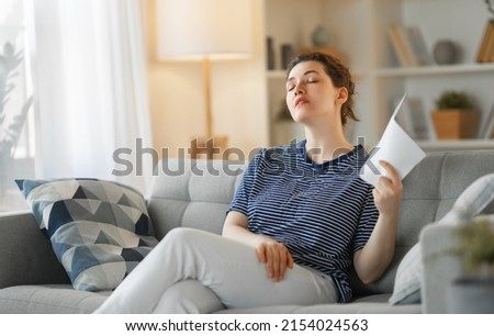 Portrait of beautiful woman fanning herself and restling at home. Royalty-Free Stock Photo #2154024563