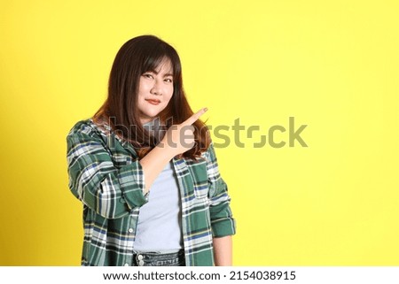 The chubby Asian woman standing on the yellow background with the casual clothes. Royalty-Free Stock Photo #2154038915