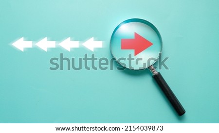 Red arrow inside of magnifier glass and different direction from white arrow for focus business disruption and technology transformation concept.