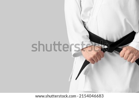 Man in karategi and with black belt on light background, closeup Royalty-Free Stock Photo #2154046683