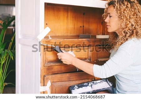 Adult woman at home restoring and painting old furniture. Recycling and renewing for circolar sustainable economy lifestyle. Environmental concept leisure people lifestyle. Royalty-Free Stock Photo #2154068687
