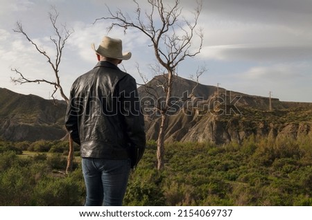 Rear view of adult man in cowboy hat in oasis of desert. Almeria, Spain