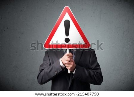Businessman holding a red traffic triangle warning sign in front of his head