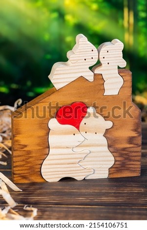 Wooden puzzle in the form of a family of handmade bears on the background of the forest.