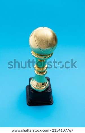 Golden basketball trophy on blue background.