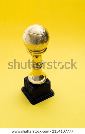 Golden basketball trophy on yellow background.