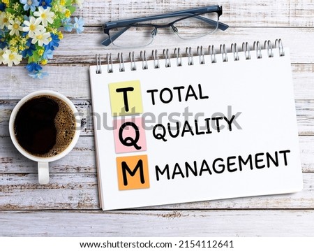 Handwriting TQM,total,quality,management on notebook,keyboard,coffee and glasses on wood table in office workplace. Business and education concept ideas. Royalty-Free Stock Photo #2154112641