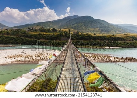 The Punakha Suspension Bridge at the Punakha Dzong. Across the Tsang Chu River to Shengana and Wangkha village. The longest suspension bridge in Bhutan and always decorated with colorful prayer flags. Royalty-Free Stock Photo #2154123741