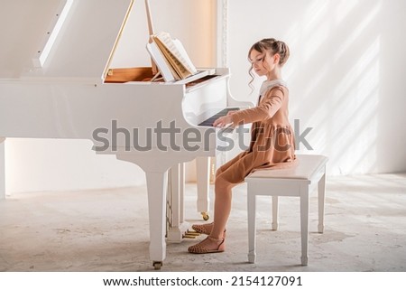 Little girl playing piano indoors Royalty-Free Stock Photo #2154127091