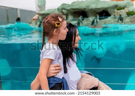 Mom and daughter enjoy watching penguin in an Aquarium