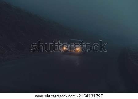 Grunge Style Photo. Car Riding on the Mountainous Road on the Foggy Night. Hazy Weather Royalty-Free Stock Photo #2154131797