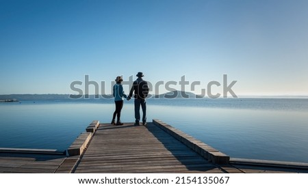 Couple holding hands, standing on the lakefront boardwalk, Rotorua. Royalty-Free Stock Photo #2154135067