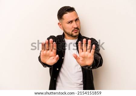 Young hispanic man isolated on white background standing with outstretched hand showing stop sign, preventing you.