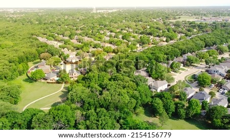 Top view upscale residential area with lush green trees, trail system, water tower in background at Flower Mound, Texas. Fly over parkside Dallas suburbs single family homes with large backyard Royalty-Free Stock Photo #2154156779