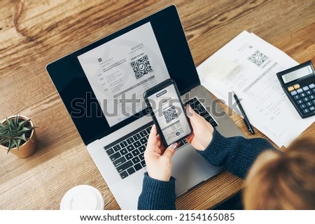 Woman scanning QR code from invoice to make payment using fast secure payment system and smartphone code reader. Business woman paying bills using express payment technology. Female using mobile phone Royalty-Free Stock Photo #2154165085