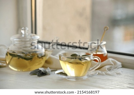 Sage tea and green leaves on white wooden windowsill