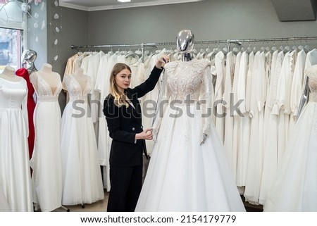 female dressmaker work at wedding salon with centimeter tape measure white elegant dress
