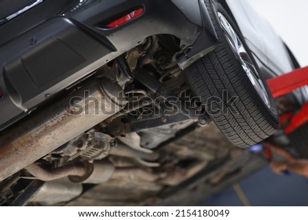 Car lifted in maintenance service for checkup, undercarriage of automobile, bottom view Royalty-Free Stock Photo #2154180049