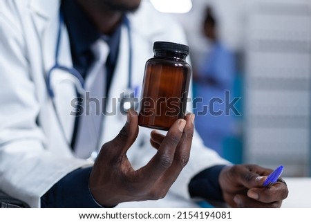 Close up of clinic physician specialist holding a bottle of pharmaceutical analgesic in personal cabinet. Hospital doctor holding prescribed antibiotic while presenting patient side effects Royalty-Free Stock Photo #2154194081