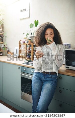Girl browsing on social media while enjoying her green smoothie. High resolution stock photo