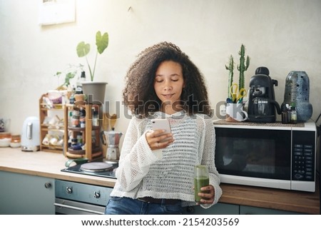 Girl browsing on social media while enjoying her green smoothie. High resolution stock photo