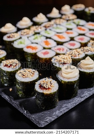 Diverse selection of maki rolls with different fillings on a black board. Selective focus. Blurred background.
