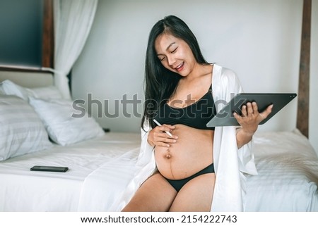 Pregnant woman works on tablet in  room on vacation. Pregnant office woman working at home during the morning.