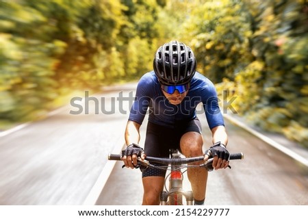 Cycling training, Cyclist speeding mountain bike on road with autumn forest side. Outdoor sport activity fun and enjoy riding. Basic techniques training on trail of athletes. Focusing on cyclist