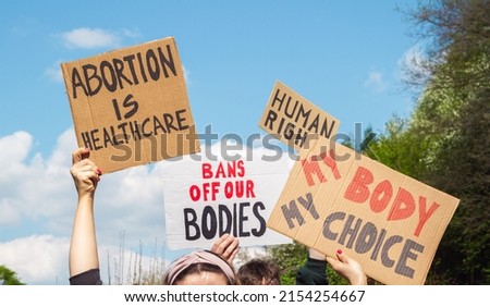 Protesters holding signs Abortion Is Healthcare, My Body My Choice, Bans Off Our Bodies, Human rights. People with placards supporting abortion rights at protest rally demonstration. Royalty-Free Stock Photo #2154254667