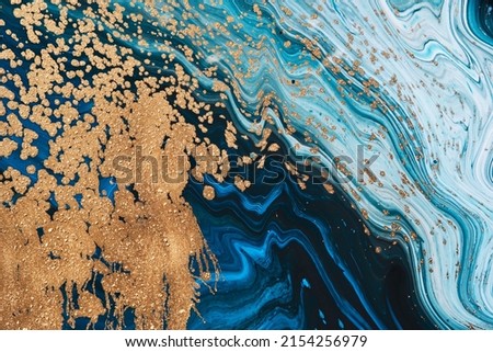 Fluid Art acrylic paints. Abstract mixing blue paint waves. Liquid golden flows splashes. Marble effect background or texture