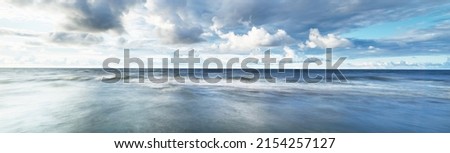 Clear sky with lots of glowing cumulus clouds above the Baltic sea shore after thunderstorm at sunset. Dramatic cloudscape. Picturesque scenery. Fickle weather, climate change. Long exposure Royalty-Free Stock Photo #2154257127