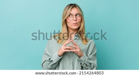 young pretty blonde woman scheming and conspiring, thinking devious tricks and cheats, cunning and betraying Royalty-Free Stock Photo #2154264803