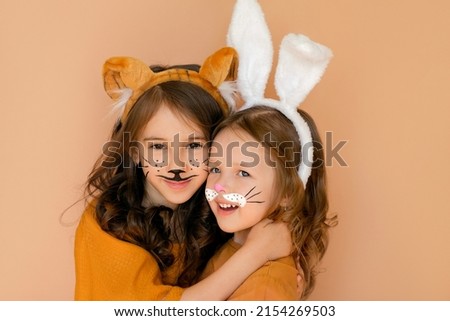 Kids with painted faces in guise of rabbit and tiger. Zodiac 2023 year according to Chinese calendar. Girl dressed up with bunny ears and makeup in anticipation new year. Symbol outgoing old year 2022