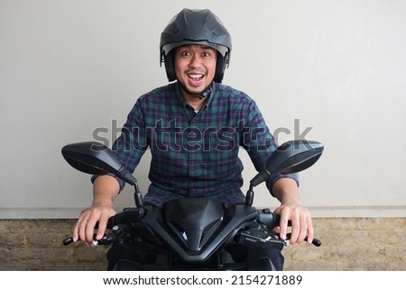 Adult Asian man showing excited expression when riding a motorcycle Royalty-Free Stock Photo #2154271889