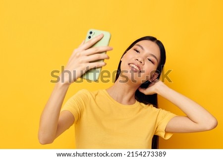 woman in a yellow t-shirt looking at the phone posing studio model unaltered