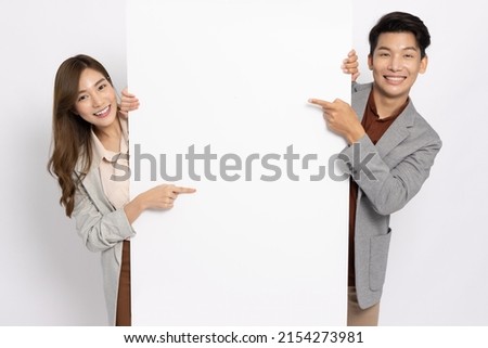 Asian businessman and businesswoman pointing and holding blank white billboard isolated on white background