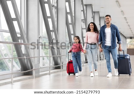 Travel Advertisement. Portrait Of Happy Arab Family Walking With Luggage At Airport, Beautiful Middle Eastern Mother, Father And Little Daughter Going To Boarding, Enjoying Traveling Together Royalty-Free Stock Photo #2154279793