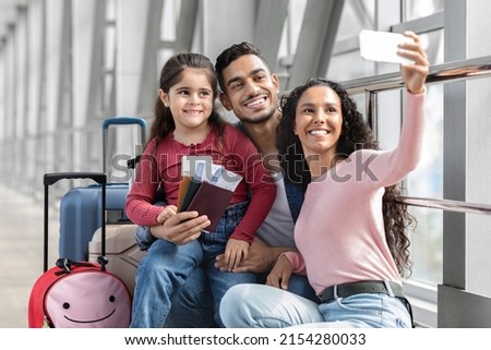 Airport Selfie. Happy Middle Eastern Family Of Three Taking Photo With Smartphone While Waiting For Flight At Terminal, Cheerful Arabic Parents And Daughter Smiling And Posing At Camera, Free Space