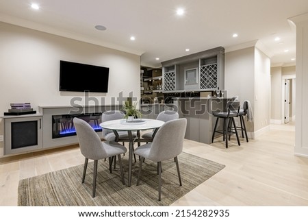 Recreation room and bar with wine rack popcorn machine large screen tv theater in grey tones and round dining table sofa and light tone hardwood floors Royalty-Free Stock Photo #2154282935