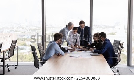 Team of interns and teacher studying marketing, working on startup project together. Business coworkers brainstorming, negotiating on sales reports at table in meeting room. Teamwork concept Royalty-Free Stock Photo #2154300863