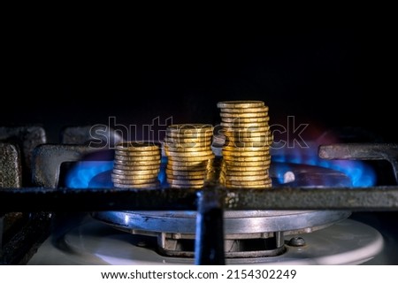 Yellow coins in the form of rising gas prices on a gas burner close-up. Background. The concept of scarcity of natural resources and rising prices for natural gas.