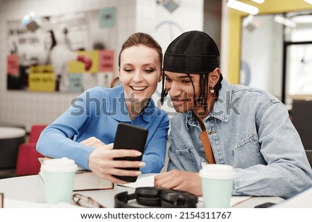 Vibrant shot of two young people taking selfie photo while having fun in college library