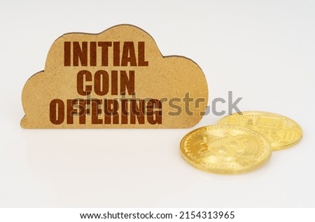 Business and technology concept. Bitcoins lie on a white surface and there is a sign - a cloud with the inscription - Initial coin offering