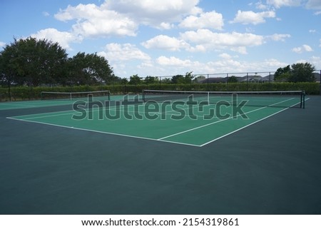 Tennis court on a sunny day with blue skies.                        