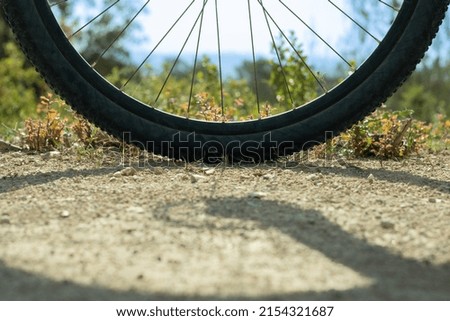 black bicycle wheel with blue sky background on dirt road with grasses
