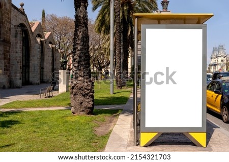 Bus stop mockup in Europe. Vertical empty blank white poster or billboard in the city street. Mock up. Street poster next to road. Sunny summer day.